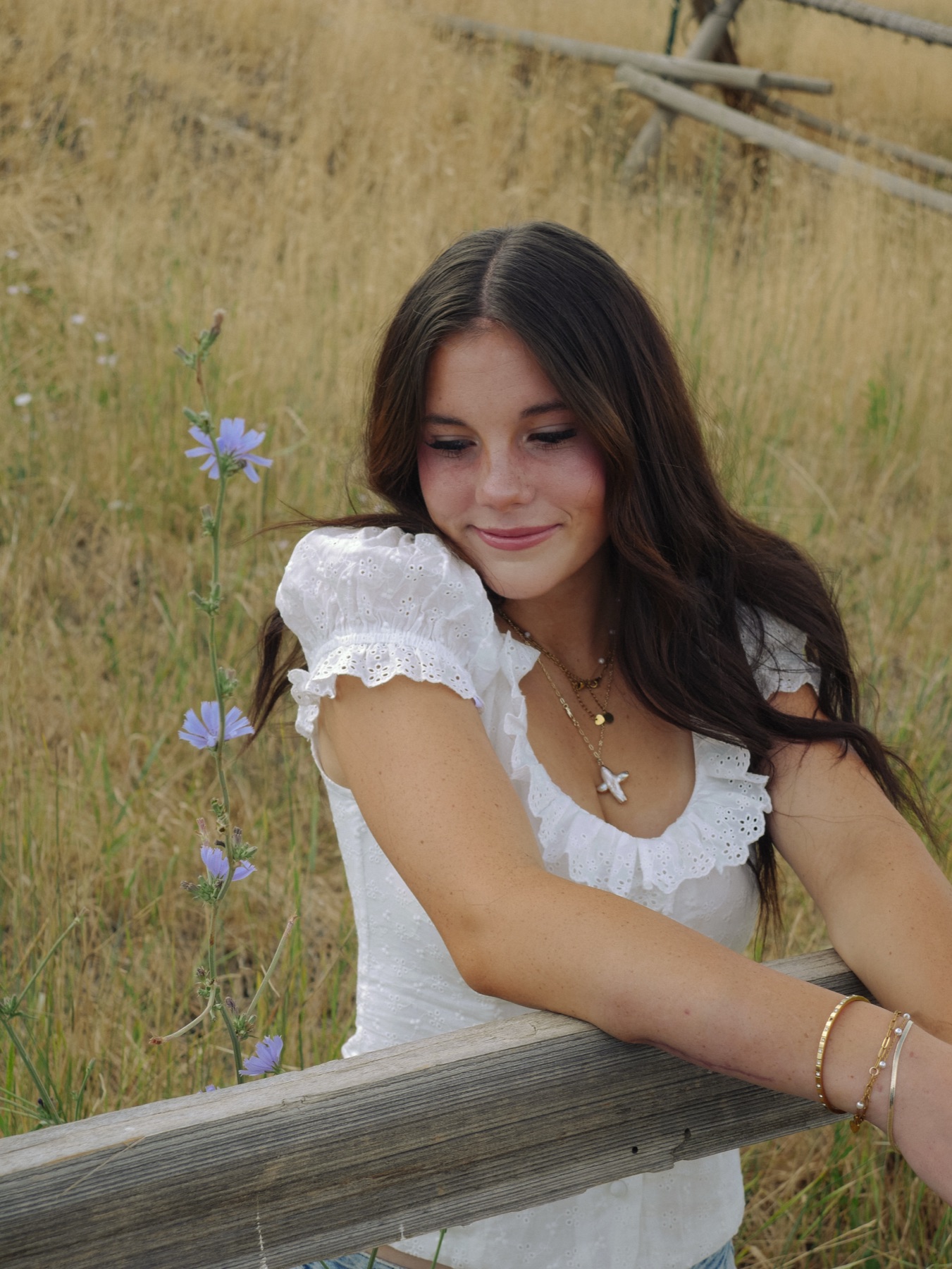 Senior portrait leaning on a wooden fence at golden hour